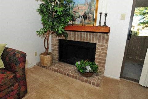 a living room with a brick fireplace and a potted plant