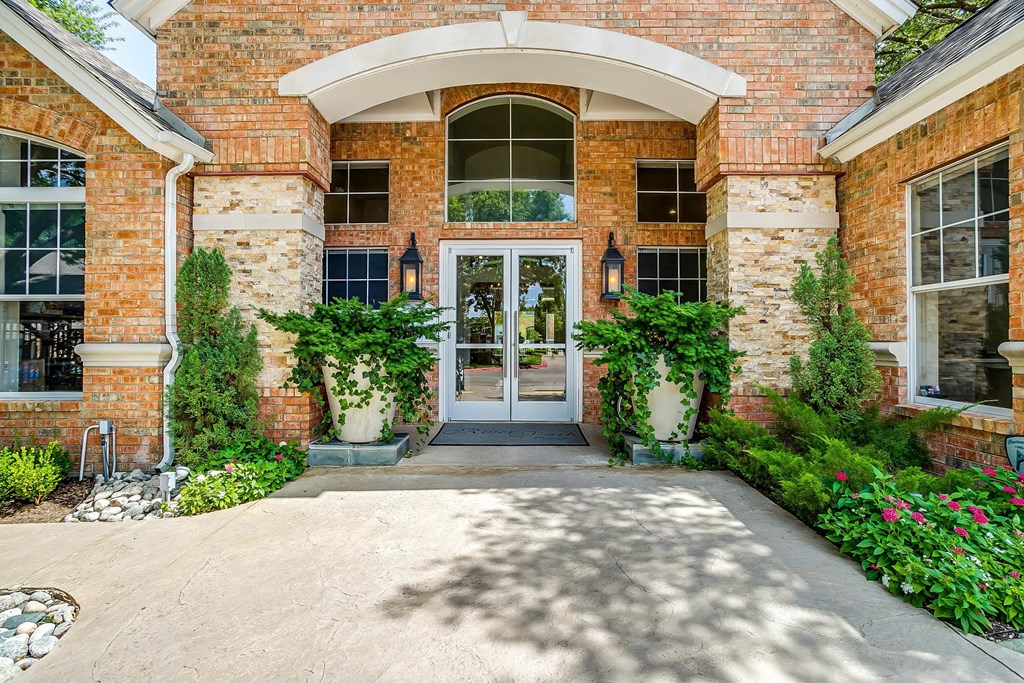 the front entrance of a brick house with a walkway and plants