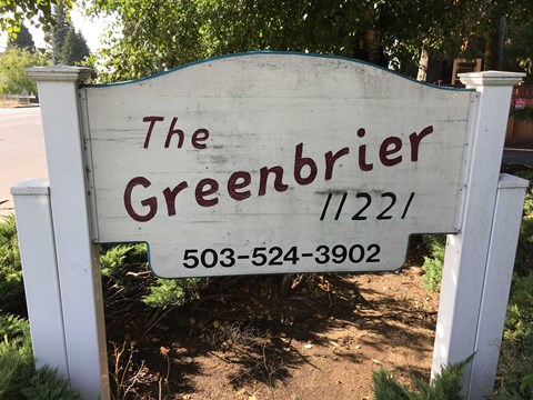 a white sign that reads the greenbler in front of a street