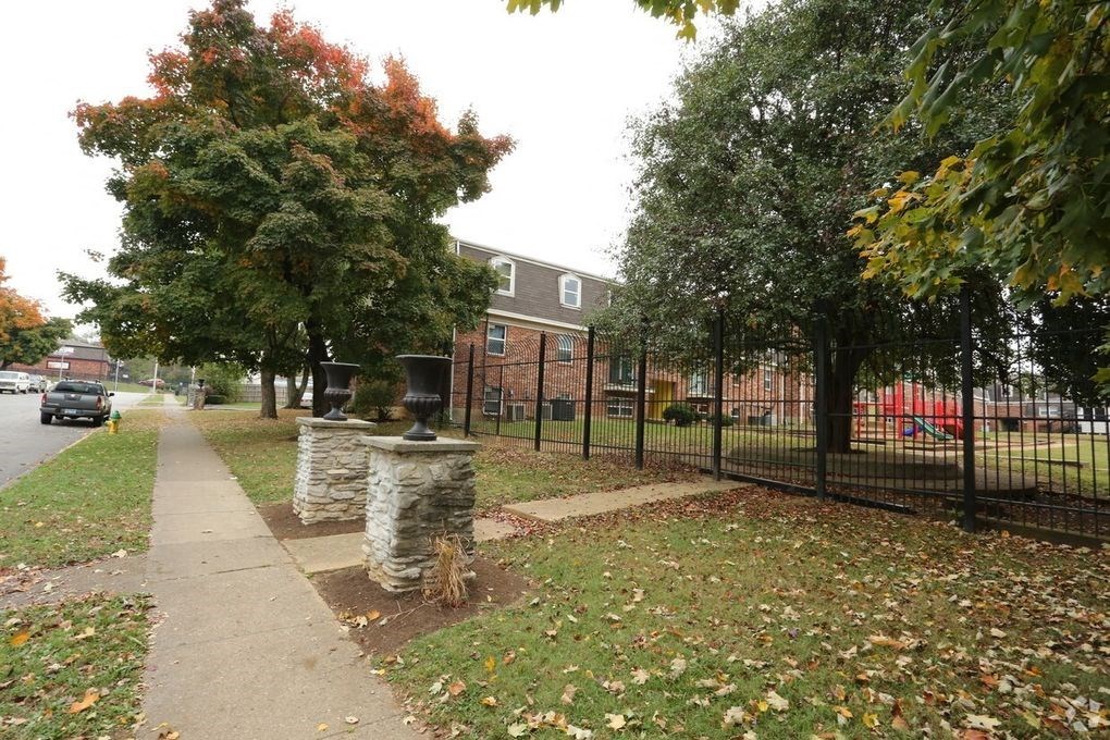 a sidewalk with trees and a black fence