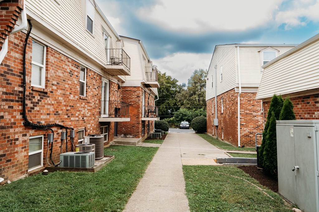 a sidewalk between two apartment buildings on a cloudy day