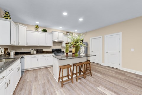 A kitchen with white cabinets and a wooden bar stool.