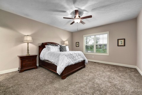 the master bedroom has a comfy bed and a ceiling fan
