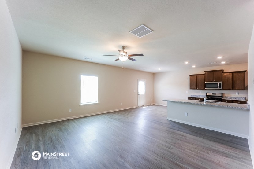 an empty living room and kitchen with a ceiling fan