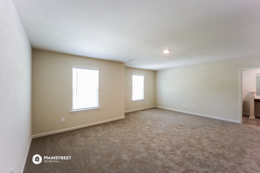 the spacious living room with carpeting and two windows