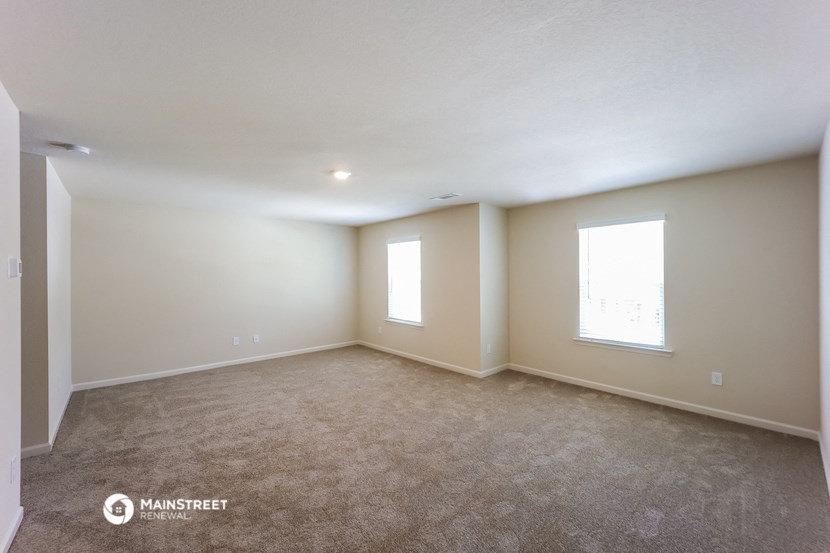 a living room with carpet and two windows