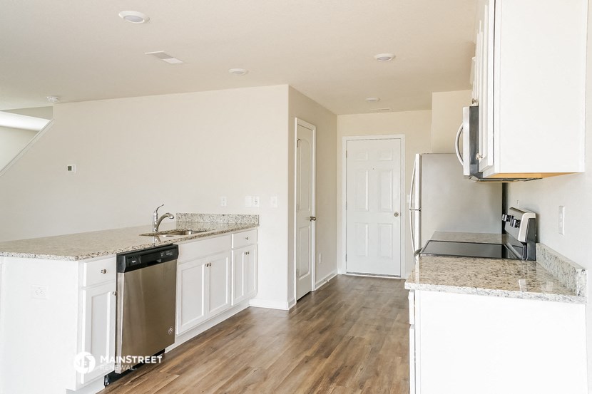 an empty kitchen with white cabinets and a counter top
