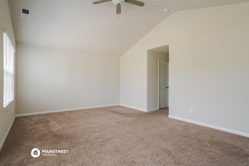 the spacious living room with carpeting and a ceiling fan