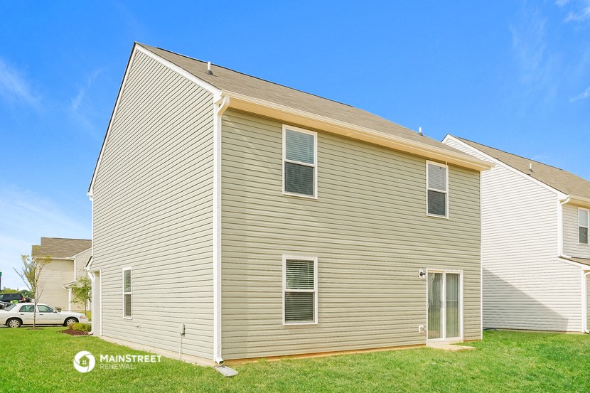 a side view of a house with a garage and a green lawn