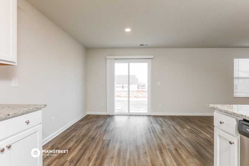the living room and kitchen of a new home with white walls and wood flooring