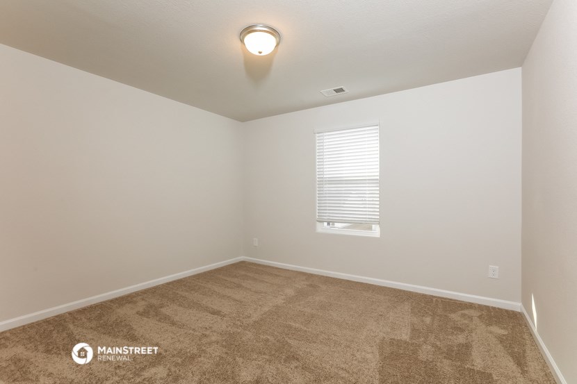 the spacious living room with carpeting and a window