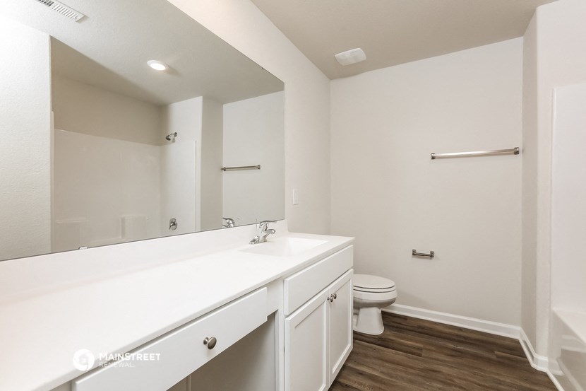 a white bathroom with a large mirror and a toilet