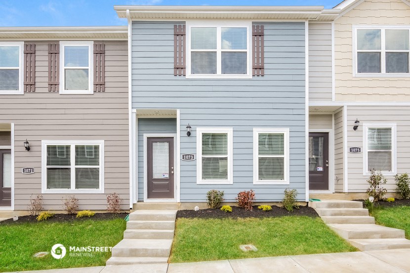 a blue house with a lawn and steps in front of it