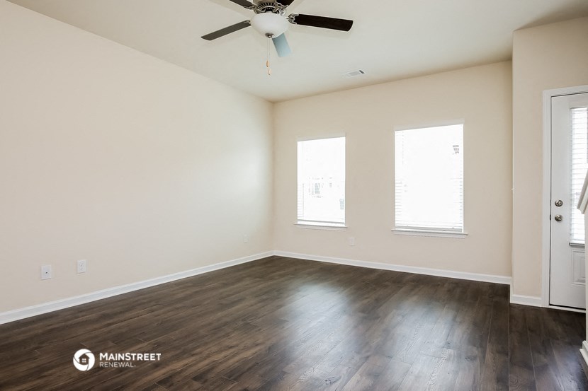 the spacious living room with hardwood floors and a ceiling fan