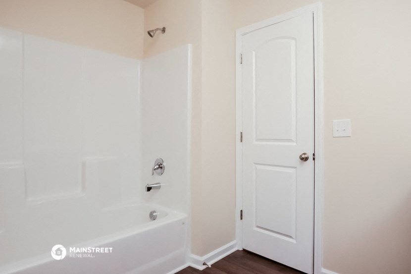 a white bathroom with a tub and a white door