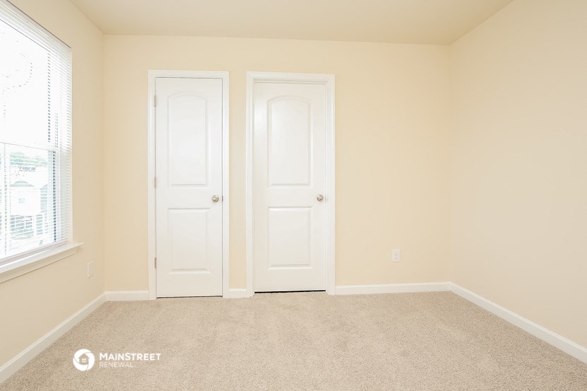 an empty room with two doors and a window