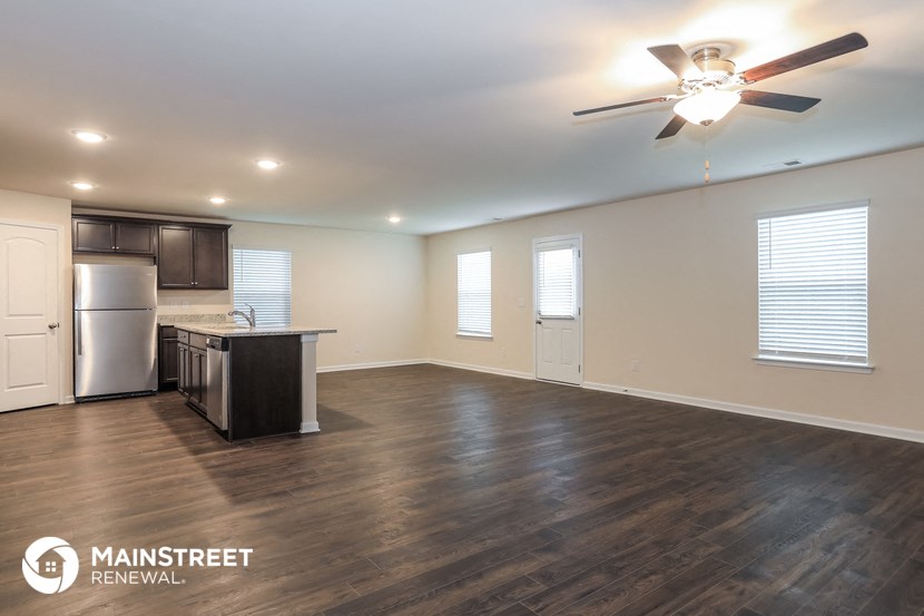 the living room and kitchen of an empty house with a ceiling fan