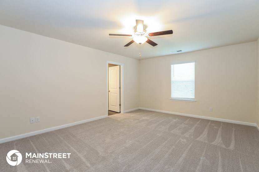 the spacious living room with ceiling fan and carpeting