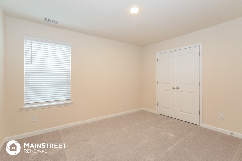 the upstairs bedroom has a large carpeted floor and a white door