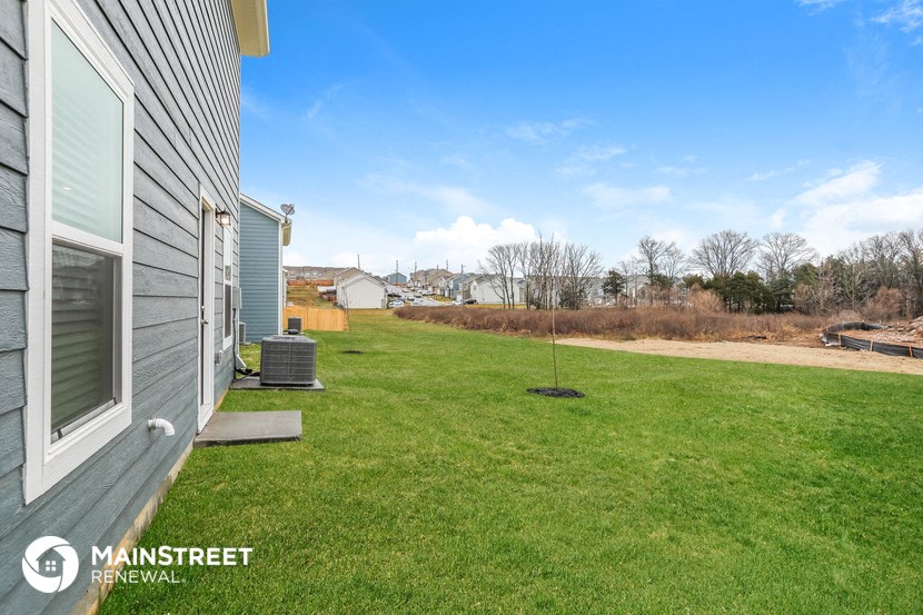 a view of the side of a house with a lawn and a yard with trees