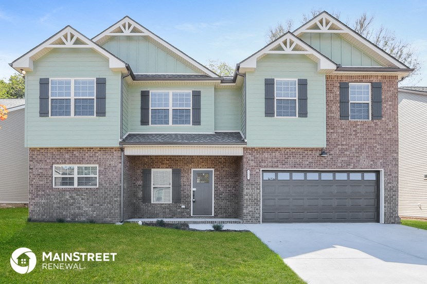 a home with a garage and a brick and green house