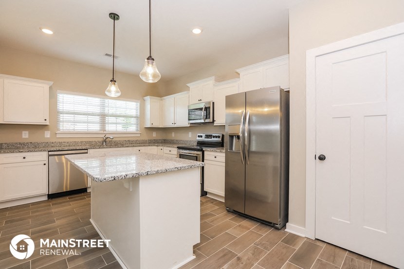 a large kitchen with stainless steel appliances and white cabinets
