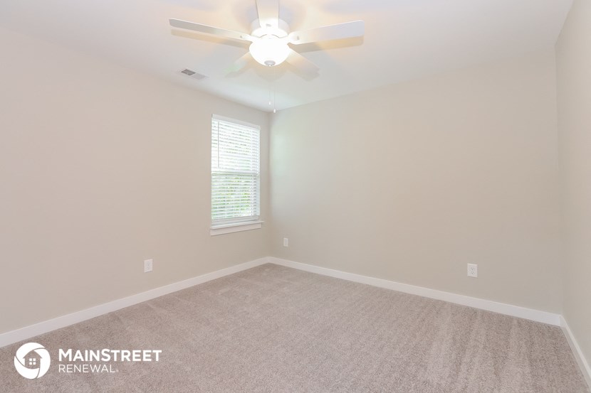 the spacious living room with ceiling fan and carpeting