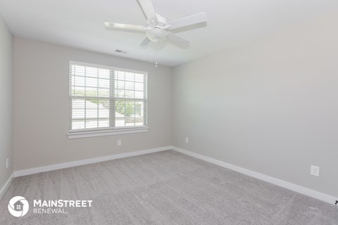 the spacious living room with carpet and a ceiling fan