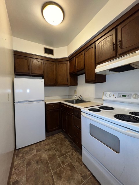 an empty kitchen with white appliances and wooden cabinets