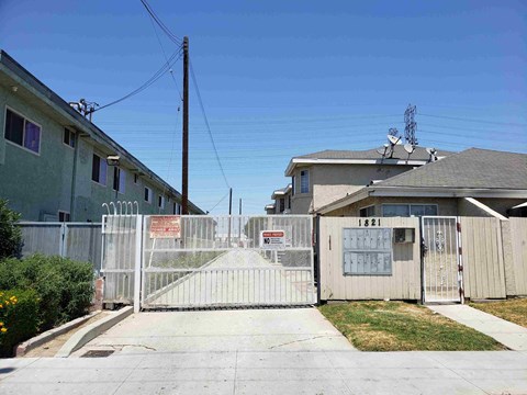 a yard with a white gate and fence in front of houses