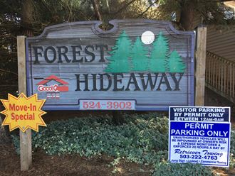 a sign for forest hideaway with a parking sign in front of it