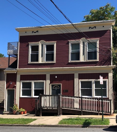 a red house with a white porch and a street sign