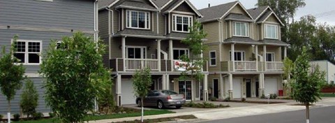 A row of houses with a car parked in front of the first one.