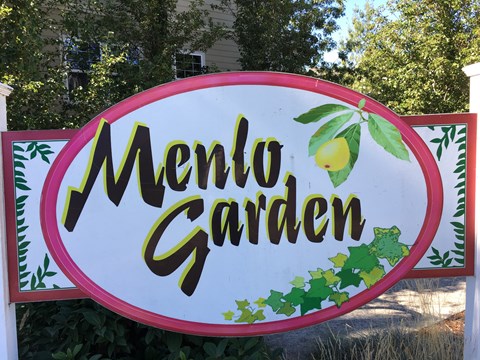 A sign that says Menlo Garden with a lemon on it.