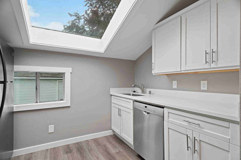 a kitchen with white cabinets and a sink and a window