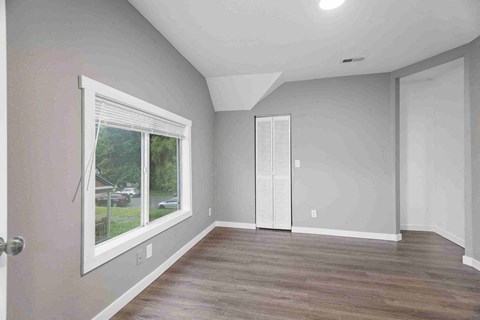 an empty living room with a large window and wooden floors
