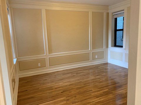 a living room with wooden floors and tan walls and a window
