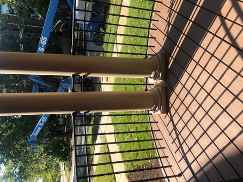 A close up of a metal fence with a blue crane in the background.