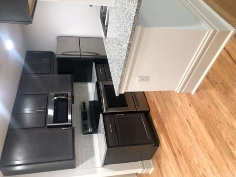 A kitchen with black appliances and a wooden floor.