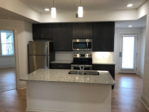 A kitchen with a granite countertop and stainless steel appliances.