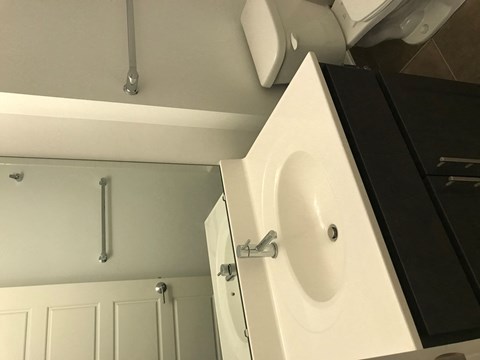 A white sink in a bathroom with a black cabinet.