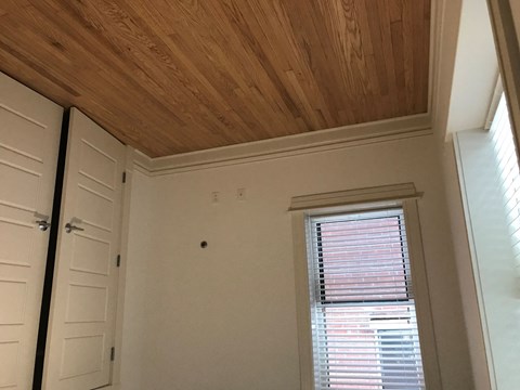 A room with a wooden ceiling and a window with blinds.
