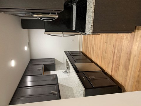A kitchen with black appliances and wooden walls.
