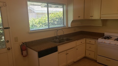 A kitchen with white cabinets and a black countertop.