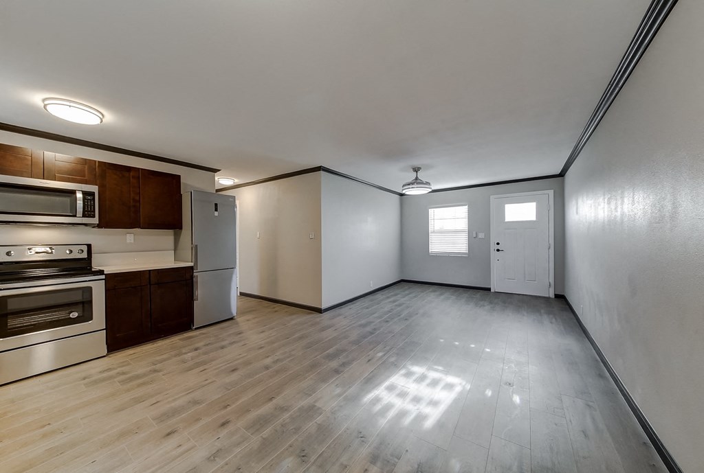 an empty living room and kitchen with white walls and wood floors