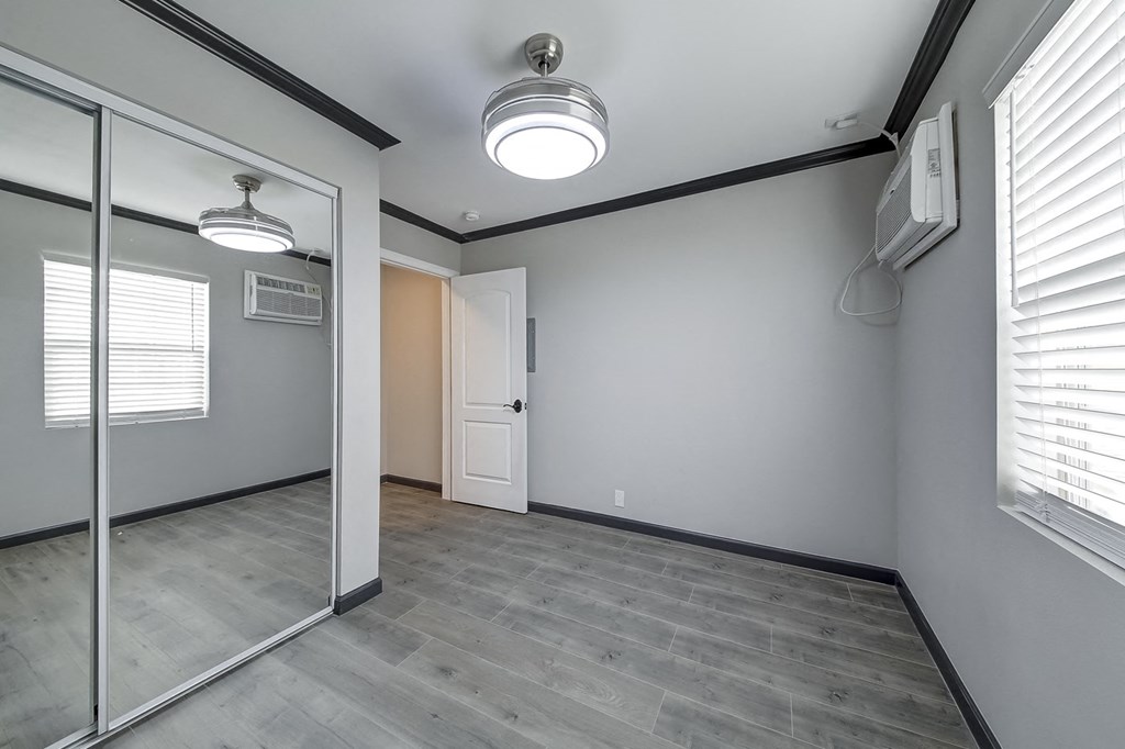 an empty room with a mirror and a door to a closet