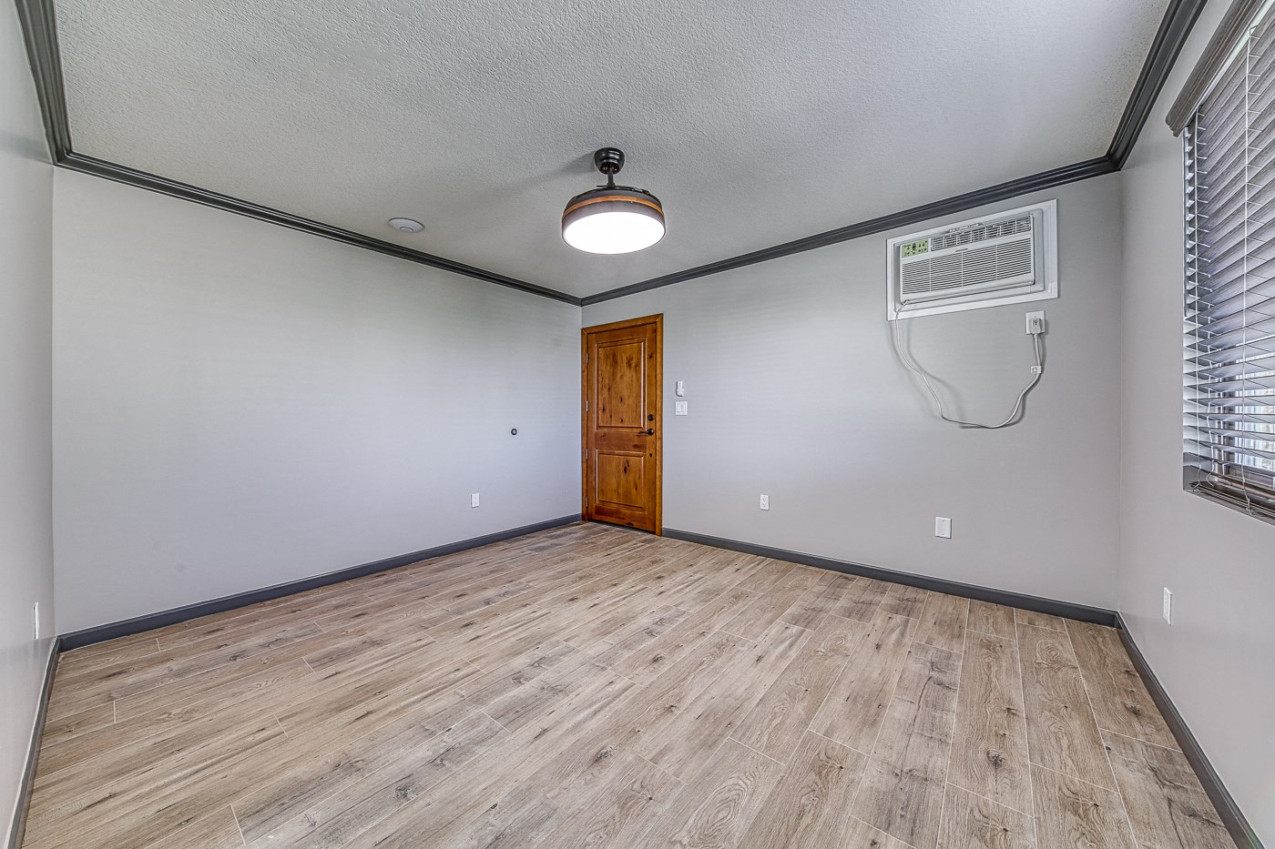 the living room of an empty house with wood flooring and a wooden door