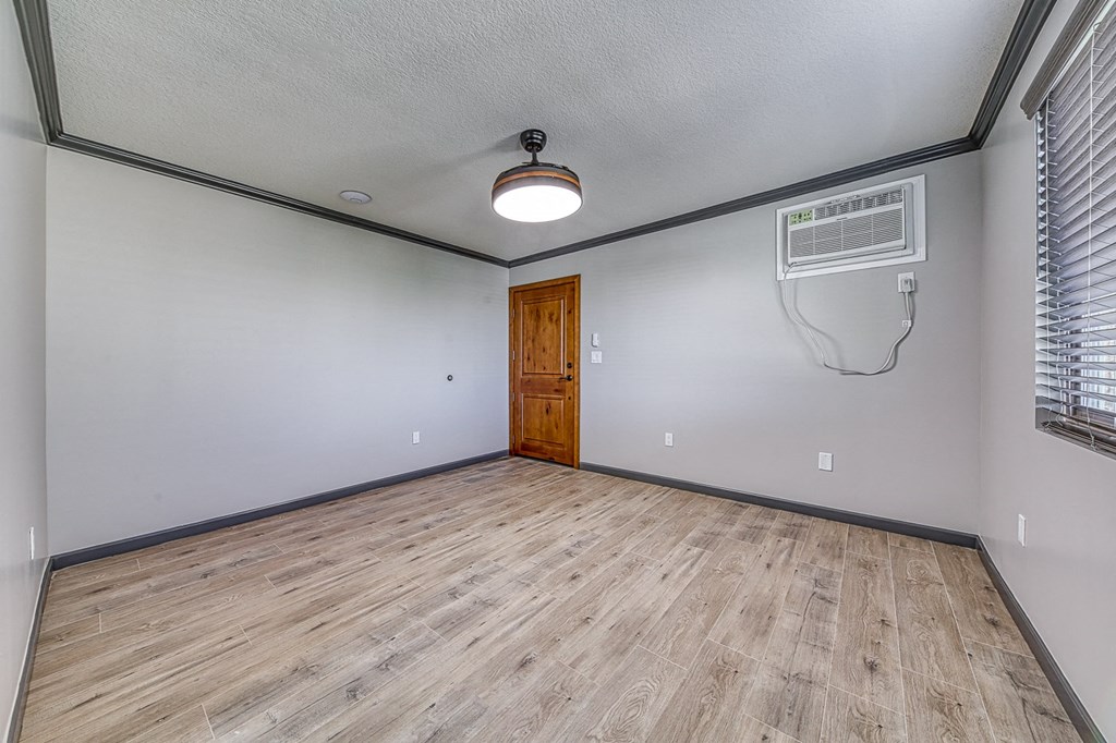 the living room of an empty house with wood flooring and a wooden door