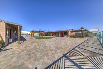 the courtyard of a motel with a brick sidewalk and a fence