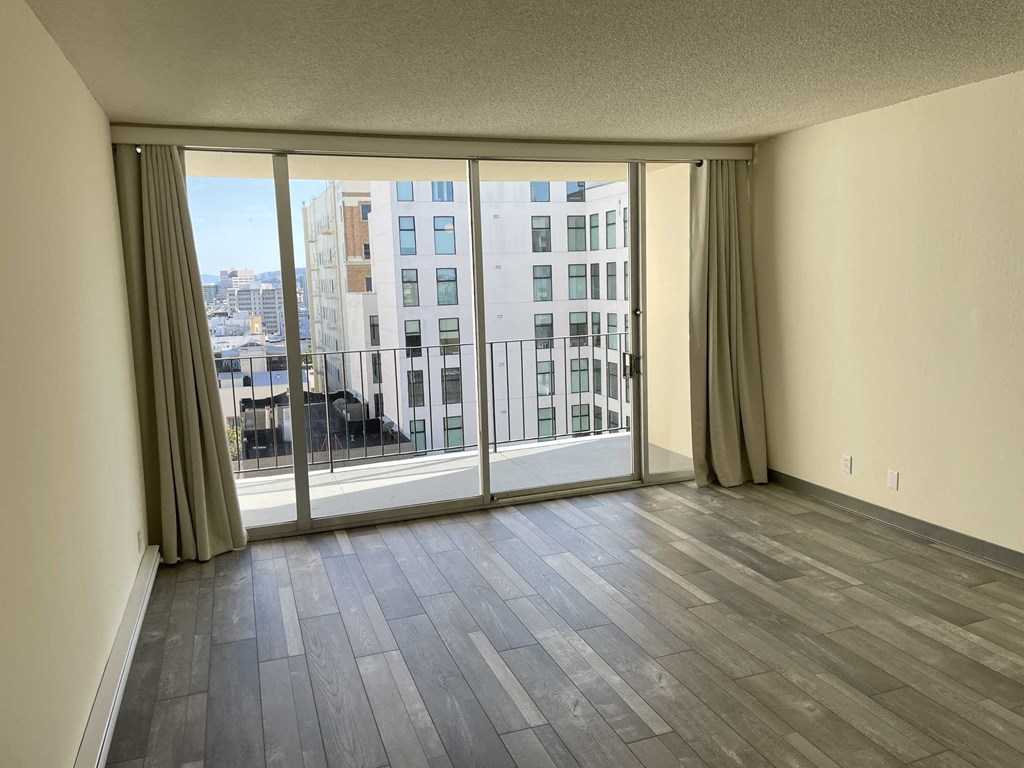 an empty living room with wood flooring and sliding glass doors
